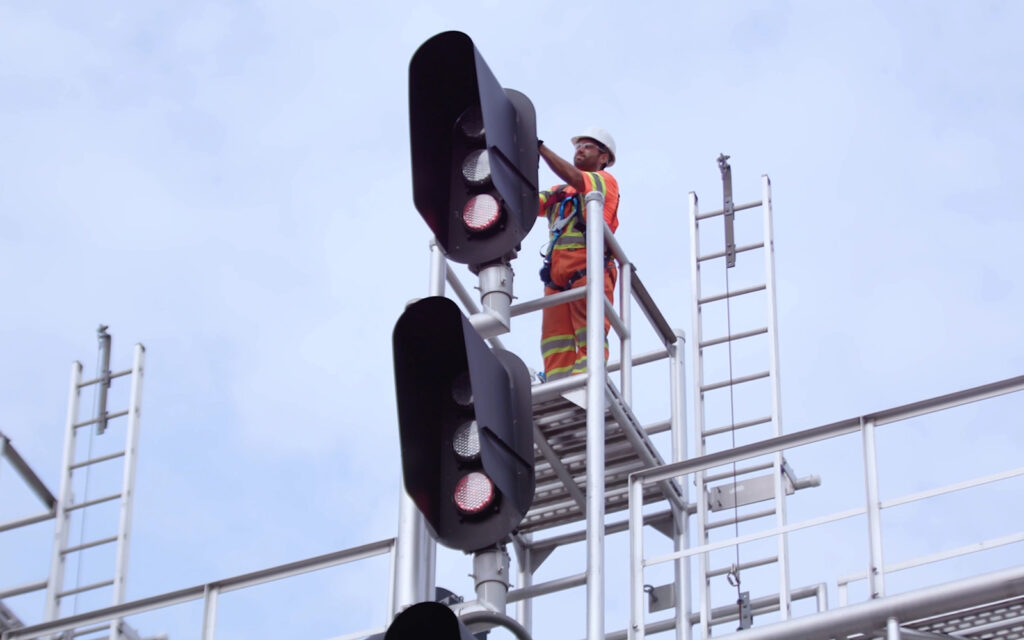 A RailWorks employee working on the back of a train traffic light.