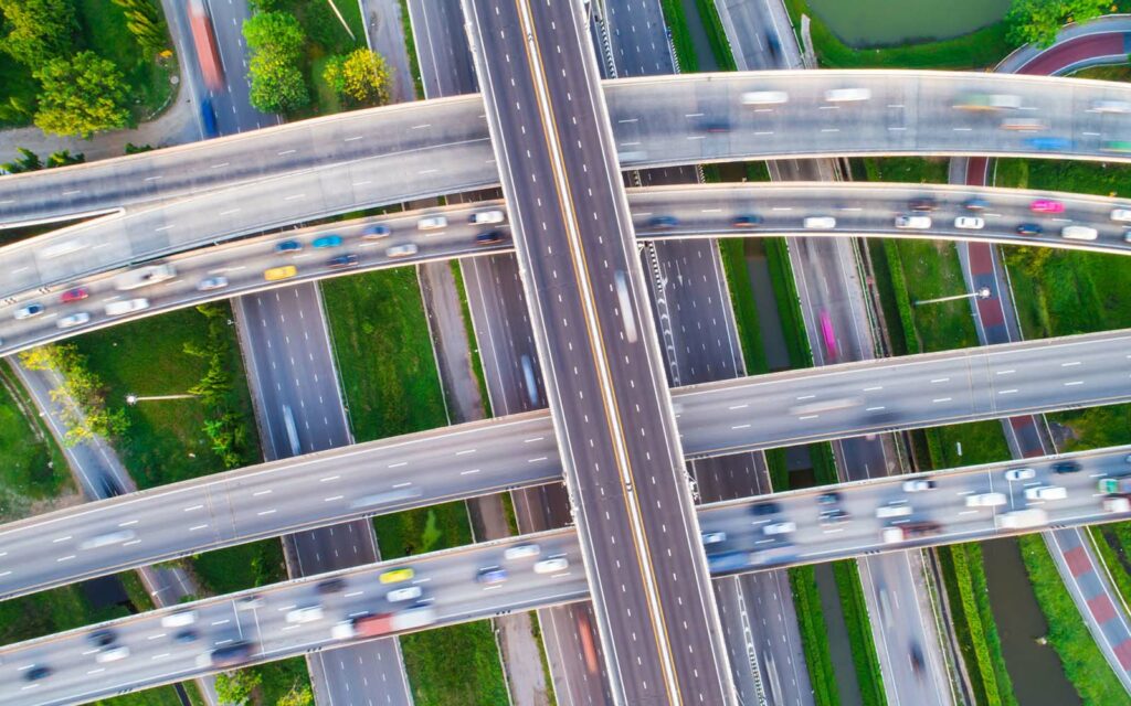 A highway system with blurred cars and has greenery in between lanes.