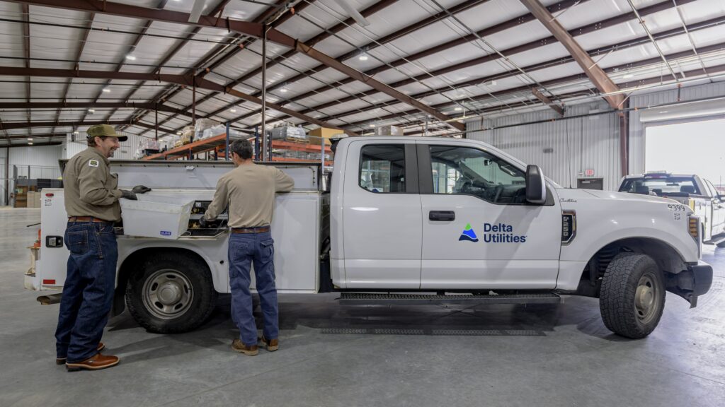 Two Delta Utilities workers by a Delta Utilities service truck.